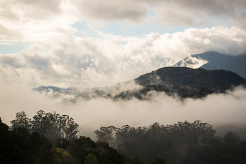 Early morning fog and mist rise over forested hills