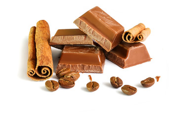 Tasty milk chocolate closeup with grains of coffee and cinnamon sticks isolated on white background
