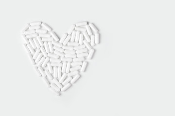 White pills forming a heart shape on a white background.