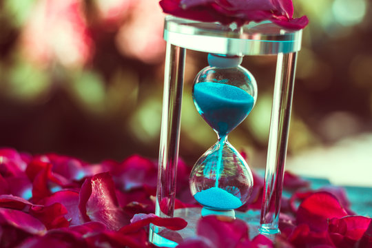 Ampulheta com areia azul e p&eacute;talas de rosas