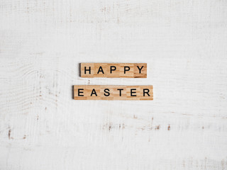 Wooden letters of the alphabet in the form of the words HAPPY EASTER on a white, isolated background. Top view, close-up. Congratulations for loved ones, relatives, friends and colleagues