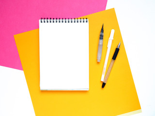 Art table colorful sheets of paper and blank notebook on white background