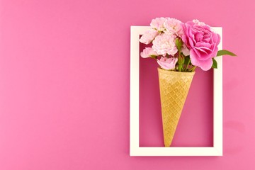 Flower card. Flower frame. Pink roses in an waffle cone  in a white  frame on a  fuchsia background. Flower ice cream.top view,copy space.Mothers Day. International Women's Day.	