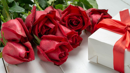 Bouquet of red rose flower and Valentine day present box on white wooden table. Can use for valentine day concept or background.