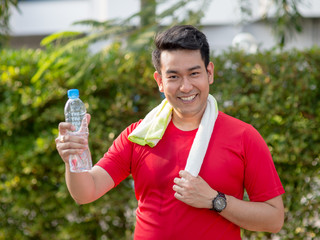 Happy Asian sport man showing a bottle of water in his hand.
