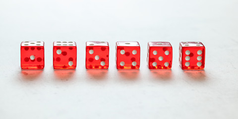 Transparent red craps dices arranged on white board, showing all numbers from one to six. Front view.