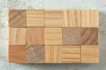 Top view - 15 small wooden cubes arranged to 3 x 5 grid, on concrete board. Letters can be added.
