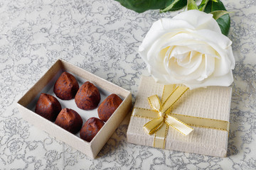 Obraz na płótnie Canvas Beautiful white rose with golden gift box and chocolate truffles for Valentine's Day