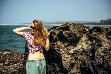 Fototapeta na wymiar Beautiful girl with naked belly relaxing on sea rocks