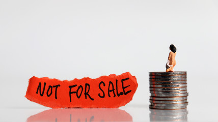 NOT FOR SALE message on the ripped paper. Stop selling people. Miniature women with the pile of...