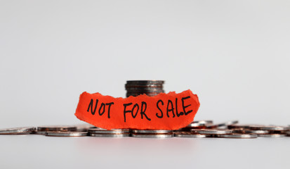 ‘NOT FOR SALE’ message on the ripped paper with the pile of coins. Not for sale campaign.
