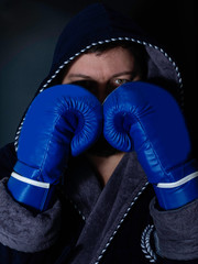 tough male boxer posing in boxing stance against dark background. Professional fighter ready for...