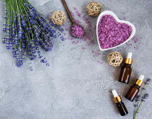 Fototapeta na wymiar Heart-shaped bowl with sea salt and fresh lavender flowers on a concrete background