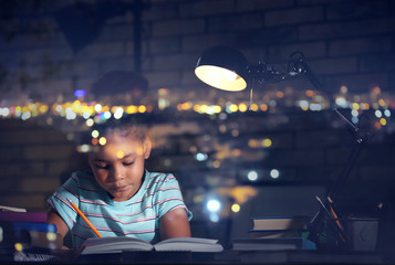 Little African-American girl doing homework in evening at home