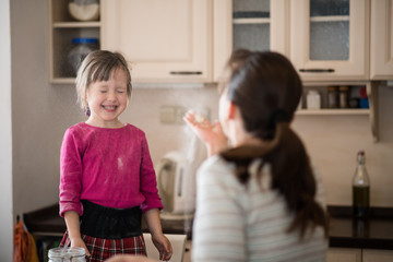 Mother blowing flour on daughter during baking