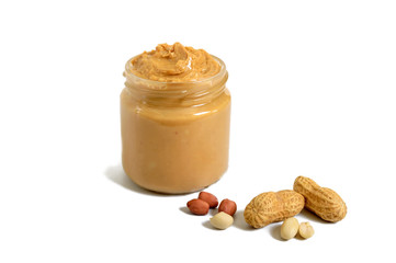 Peanut butter in a glass jar with peanuts isolated on white background.  A traditional product of...