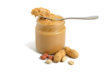 Peanut butter in a glass jar and a whole peanut isolated on white background.  A traditional product of American cuisine.