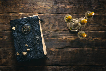 Ancient magic book and burning candle on a wooden table background with copy space. Spellbook.