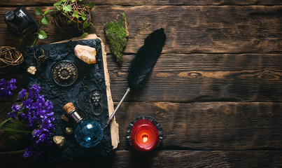 Spell book, magic potions and other various witchcraft accessories on the wizard table background with copy space. - obrazy, fototapety, plakaty