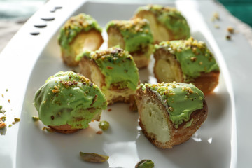 Tasty pistachio eclairs on plate, closeup