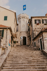 HERCEG NOVI, MONTENEGRO - November 30, 2018: the old town gate with the small clocktower surrounded by old houses, cafes and bars - Image.