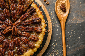 Board with tasty pecan pie on grey background
