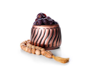 Tasty sweet dates in bowl with prayer beads on white background