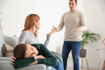 Sad little boy with his quarreling parents at home