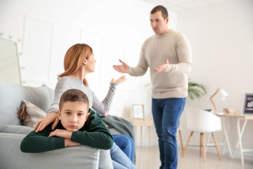 Sad little boy with his quarreling parents at home