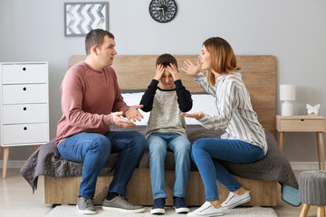 Sad little boy covering ears while his parents arguing at home