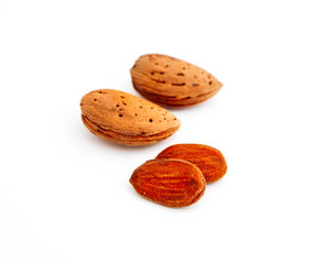 A pile of wild peeled almond nuts and kernels, closeup, isolated on white background.