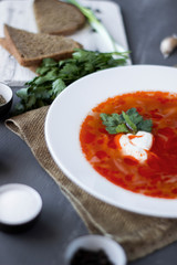 Traditional Ukrainian Russian borsch with sour cream and white beans on a dark background, macro. Red vegetable beetroot soup.