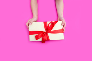 Children's hands hold gift box on a pink background. A concept by the Mother's Day. Vintage toning. Father's day. Birthday.