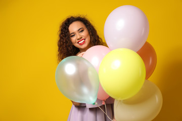 Beautiful young woman with balloons on color background