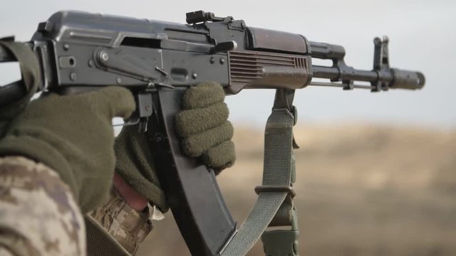 Officer shooting from automated rifle AK 74M in autumn in a firing range in slo-mo 