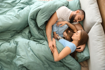 Happy family sleeping in bed at home