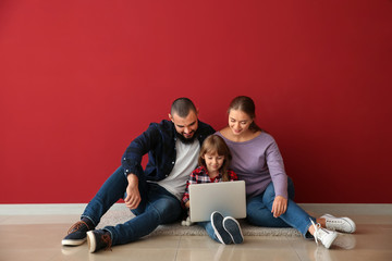 Happy family with laptop sitting on floor in their new flat