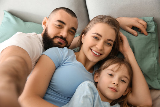 Happy family taking selfie in bed
