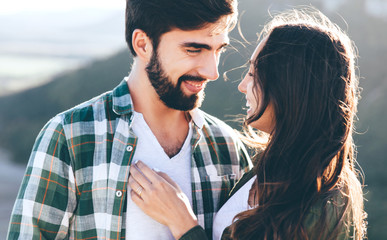 Young beautiful couple walking outside on beautiful sunset. Perfect romantic landscape for lovestory. Two hipsters-lovers hugging and kissing. Valentine's day concept.