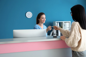Female receptionist receiving payment for medical service from patient in clinic