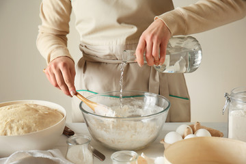 Young woman preparing dough for bread at table