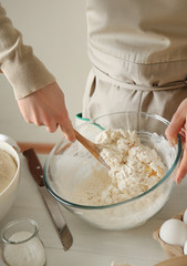 Young woman preparing dough for bread at table