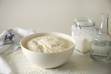 Bowl with fresh dough for bread on light table