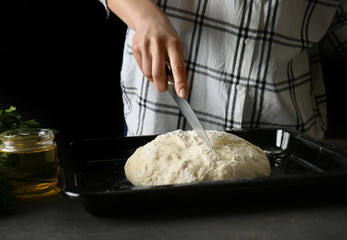 Young woman preparing fresh dough for bread for baking at table