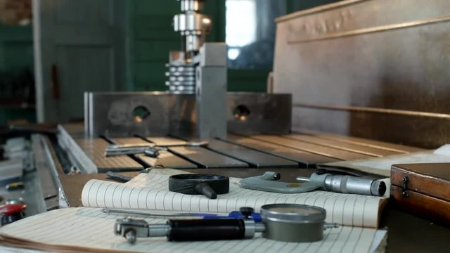 A private workshop for working with metal parts, in the background a drilling machine drills a hole in the pulley, on the table lie measuring tools, production