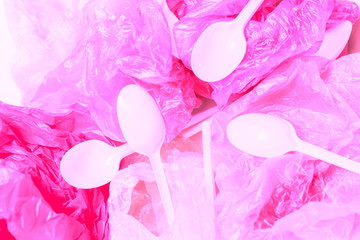 Pink plastic bags and plastic spoons background. Plastic-free concept. Emvinronment pollution flat lay, top view.