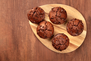 Chocolate muffins, shot from above on a dark rustic wooden background with a place for text