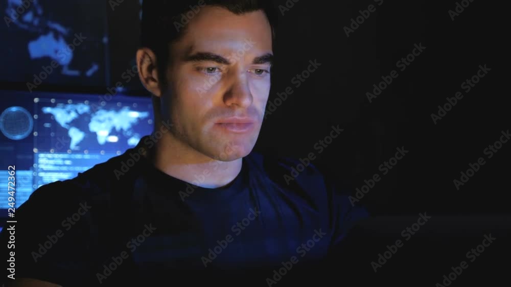 Wall mural portrait of developer programmer working on computer in a data center filled with monitor screens.