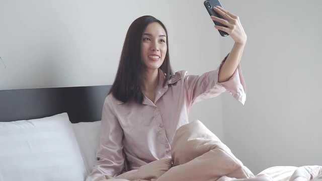 Young teenage beautiful woman taking photo or making selfie in her bedroom