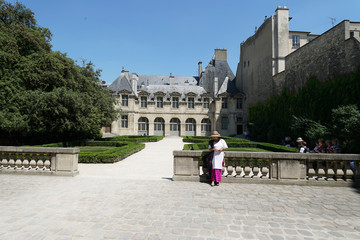 Obraz premium Femme avec chapeau posnt sur une balustrade du jardin de l'hötel de Sully à Paris